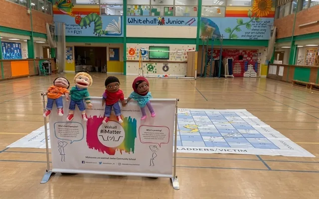 The school hall on a workshop day, with the murals above and the pupils own puppet board